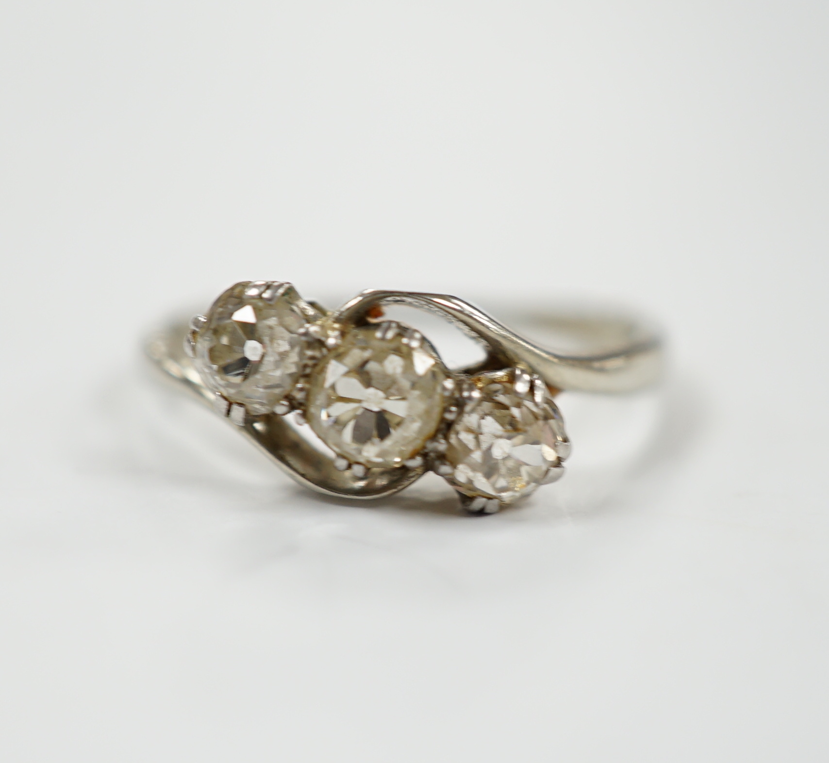 An 18ct, plat and three stone old mine cut diamond set crossover ring, size N, gross weight 2.3 grams.